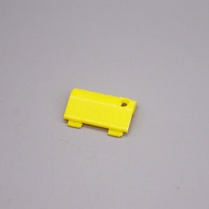 May include: A small, yellow plastic part with a hole in the center. It has two small tabs on each side.