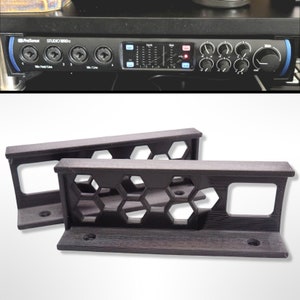 May include: Two black 3D printed brackets with a honeycomb design. The brackets are designed to mount a piece of equipment to a wall or shelf.