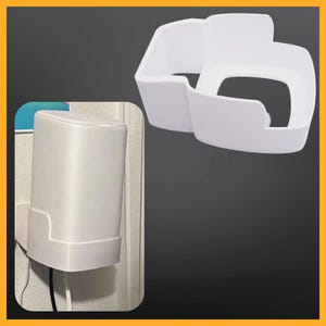 Könnte beinhalten: Weiße Wandhalterung aus Kunststoff für einen intelligenten Lautsprecher. Die Halterung ist so konzipiert, dass der Lautsprecher sicher an der Wand befestigt wird. Der Lautsprecher ist nicht im Lieferumfang enthalten.