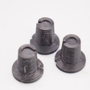 Op de afbeelding: Drie zwarte kunststofknoppen met een getextureerd oppervlak en een verhoogde ring rond de bovenkant.