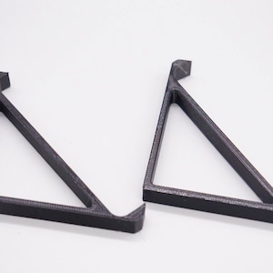 Puede incluir: Dos soportes de estante triangulares negros hechos de plástico.