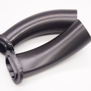 Może przedstawiać: Dwa czarne, zakrzywione uchwyty z tworzywa sztucznego o gładkim wykończeniu. Uchwyty mają zaokrąglony koniec i płaski koniec z prostokątnym otworem.