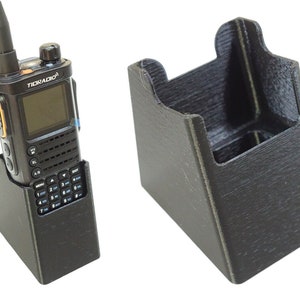May include: A black two-way radio with a charging stand and a separate charging stand. The radio has a screen and a keypad. The text "TIORADIO" is on the radio.