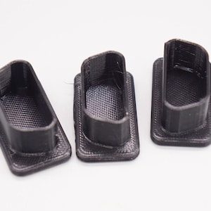 May include: Three black plastic rectangular-shaped end caps with a rounded top and a textured surface.
