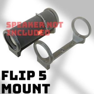 Könnte beinhalten: Dunkelgraue Flip 5 Halterung mit passendem Lautsprecher. Die Halterung hat zwei kreisförmige Halterungen und einen Verbindungssteg mit Schraubenlöchern. Der Text "SPEAKER NOT INCLUDED" und "FLIP 5 MOUNT" sind sichtbar.