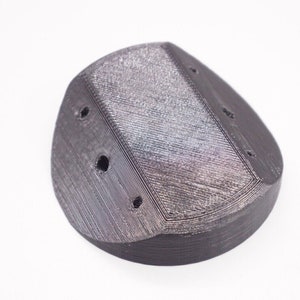 May include: A 3D printed black plastic part with a textured surface and four holes.