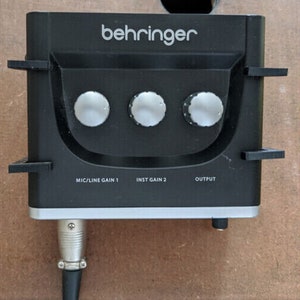 May include: A black Behringer audio mixer with three knobs, labelled "MIC/LINE GAIN 1", "INST GAIN 2", and "OUTPUT".