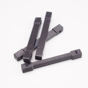 May include: Four black plastic pieces with a rectangular shape and a small hole at each end.