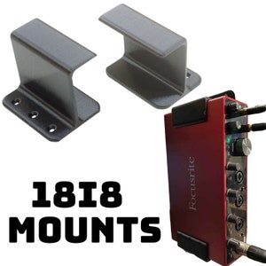 May include: Two gray metal mounting brackets and a red Focusrite 18i8 audio interface. The brackets are designed to hold the interface securely. The text "1818 MOUNTS" is displayed in bold, black letters.