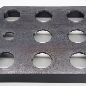 Può includere: Un organizzatore in plastica nera con nove tagli circolari. L'organizzatore è progettato per contenere piccoli oggetti, come monete o gioielli.