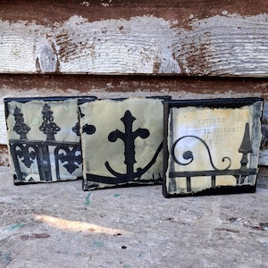 May include: Three square art pieces with black frames. Each features a different black silhouette: a decorative fence, an anchor, and a section of a wrought iron fence with text. The backgrounds are a faded parchment color.