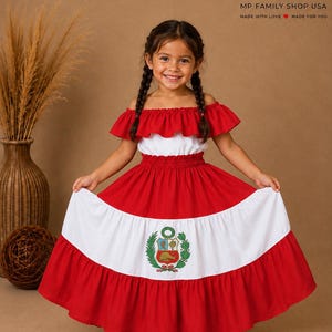 Peut inclure: Une robe rouge et blanche à épaules dénudées avec un décolleté à volants et une jupe à étages. Le centre du panneau blanc de la jupe affiche les armoiries colorées du Pérou, comprenant un bouclier, une vigogne, un quinquina et une corne d'abondance.