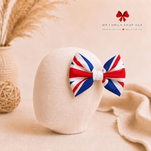 Puede incluir: Un lazo para el cabello con el patrón de la bandera Union Jack en rojo, blanco y azul. El lazo está centrado en una cabeza de maniquí beige. El texto superior dice MP FAMILY SHOP USA, MADE WITH LOVE, MADE FOR YOU, con un pequeño icono de corazón rojo.