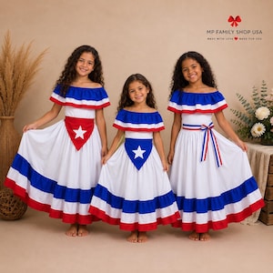 Puede incluir: Tres vestidos blancos con escote de hombros descubiertos, con rayas horizontales rojas y azules en el dobladillo y el escote. Cada vestido muestra un panel triangular azul con una estrella blanca en el corpiño. El texto MP FAMILY SHOP USA es visible.