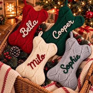 May include: Four bone-shaped Christmas stockings in red, green, cream, and gray knit fabric with cable-knit patterns. Each stocking features a name embroidered in cursive script: Bella in white, Cooper in white, Milo in red, and Sophie in green.