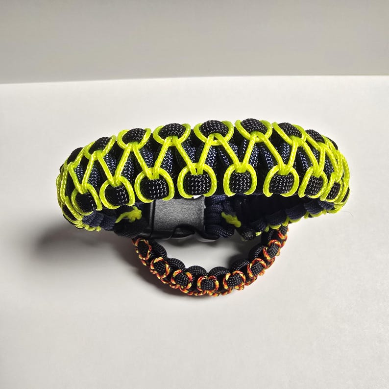 Pu&ograve; includere: Due braccialetti in paracord. Il braccialetto pi&ugrave; grande &egrave; nero con dettagli giallo neon, e il pi&ugrave; piccolo &egrave; nero con dettagli arancioni. Entrambi i braccialetti hanno un design intrecciato e una chiusura a fibbia.