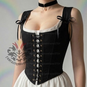 May include: A black corset bodice featuring a front lace-up closure with gold-toned grommets and black ribbon ties at the shoulders. The garment is worn over a white undergarment, and a black velvet choker with a small pendant is worn around the neck.