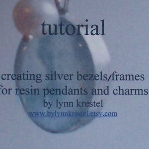 May include: A tutorial on creating silver bezels and frames for resin pendants and charms, by Lynn Krestel. The image shows a close-up of a silver bezel with a pearl on top.