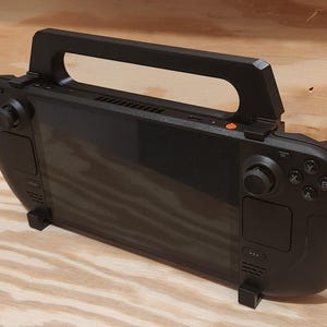 May include: A black handheld gaming device with a built-in screen, two joysticks, and a carrying handle. The device has a black and white button layout with letters A, B, X, and Y.