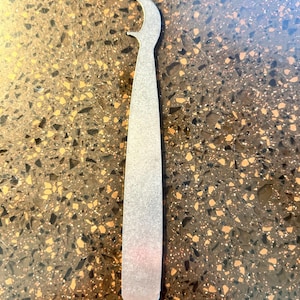 May include: A silver metal bottle opener with a curved handle and a pointed tip.