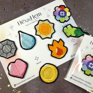 以下が含まれることがあります： 宝石、水滴、太陽、炎、ハート、コイン、葉、花の刺繍アイロン接着パッチのコレクション。パッチは、ブランド名「Hex & Hem」とEtsyショップURLが記載された白い背景にあります。