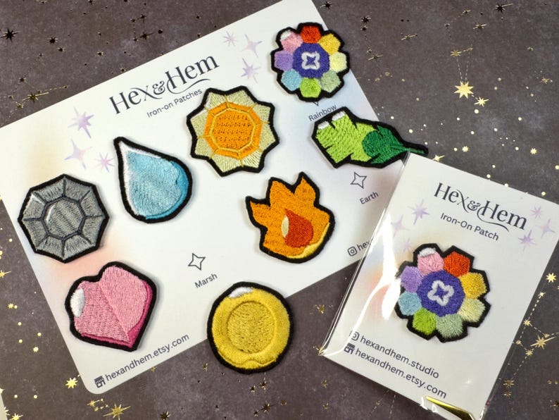 Puede incluir: Parches bordados para planchar con varios dise&ntilde;os, incluyendo una gema, una gota de agua, un sol, una llama, un coraz&oacute;n, una moneda, una hoja y una flor. Los parches est&aacute;n sobre un fondo blanco con la marca "Hex & Hem".