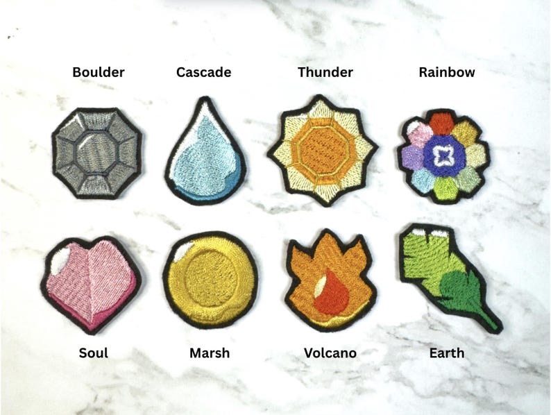 Puede incluir: Una colecci&oacute;n de parches bordados en varias formas y colores. Los parches incluyen una gema gris etiquetada como "Boulder", una l&aacute;grima azul etiquetada como "Cascade", un sol amarillo etiquetado como "Thunder" y una flor etiquetada como "Rainbow". Otros parches incluyen un coraz&oacute;n rosa etiquetado como "Soul", una moneda de oro etiquetada como "Marsh", una llama etiquetada como "Volcano" y una hoja verde etiquetada como "Earth".