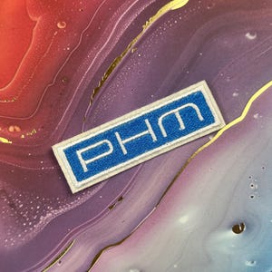 May include: A rectangular patch with the letters "PHM" in white, set against a blue background. The patch has a white border and is displayed on a colorful, marbled surface with gold accents.