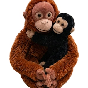 May include: A plush orangutan hugging a black plush monkey. The orangutan has brown fur, a light brown face, and large, round eyes. The monkey has black fur and a light brown face. The toys are soft and cuddly.
