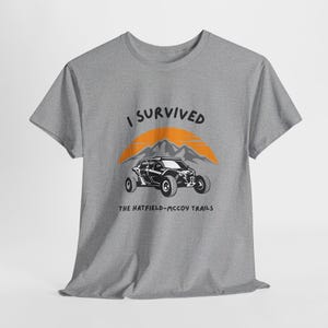 May include: Gray t-shirt with the text "I Survived The Hatfield-McCoy Trails" and a black and white illustration of an off-road vehicle driving through a mountain landscape.
