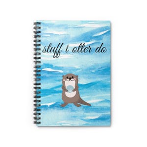 Könnte beinhalten: Ein blaues und weißes Aquarell-Notizbuch mit einem niedlichen Otter, der eine Muschel hält. Das Notizbuch hat eine Spiralbindung und den Text "stuff i otter do" auf der Vorderseite.