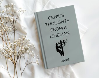 Puede incluir: Un libro gris claro titulado "GENIUS THOUGHTS FROM A LINEMAN" con una silueta de un liniero en un poste de electricidad. El nombre "DAVE" está impreso en la parte inferior. El libro está sobre una superficie blanca con flores blancas.