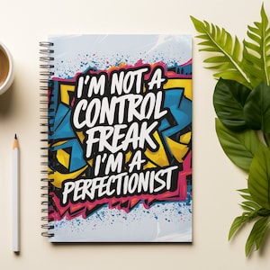 May include: A spiral bound notebook with a colorful graffiti design. The notebook cover features the text "I'm not a control freak I'm a perfectionist".