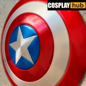 Pu&ograve; includere: Uno scudo di Captain America con una combinazione di colori rosso, bianco e blu. Lo scudo presenta una stella argentata in un cerchio blu al centro, circondata da bande rosse e argentate concentriche. Il testo "COSPLAY hub" &egrave; nell'angolo in alto a destra.