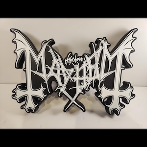 May include: A black and white wall sign featuring the word MAYHEM in a stylised, jagged font with bat-like wing accents on the outer letters and cross-shaped details at the bottom. The centre includes smaller, intricate white text.