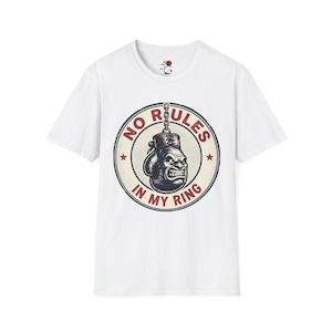 May include: White t-shirt featuring a circular graphic with a boxing glove and the text "NO RULES IN MY RING". The graphic is in shades of blue, red, and beige. The shirt has short sleeves and a crew neck.