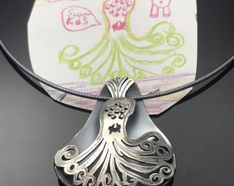 May include: A silver necklace with a pendant shaped like an octopus. The octopus has a black body and silver tentacles. The pendant is hanging over a drawing of an octopus.