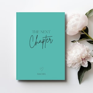 May include: A teal hardback book with the text THE NEXT Chapter printed in black, featuring a small heart icon and the name RACHEL printed below it. The book is positioned next to two large, pale pink peony flowers with green leaves.