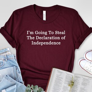 Puede incluir: Una camiseta color burdeos con texto blanco que dice "I'm Going To Steal The Declaration of Independence".