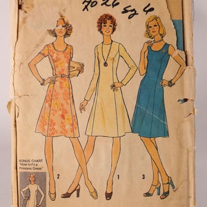May include: A vintage Simplicity sewing pattern for a basic dress in sizes 4, 6, 8, 10, 12, 14, 16, 18, and 20. The pattern features three different dress styles: a floral print dress, a cream dress, and a blue dress. The pattern includes a bonus chart for fitting a princess dress.