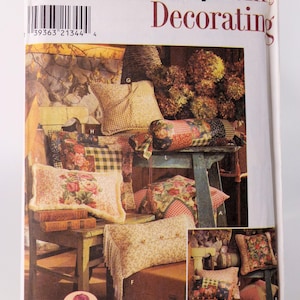 Puede incluir: Un sobre de patrón Simplicity Home Decorating con el número 8044 en la parte delantera. El sobre muestra una variedad de almohadas y cojines en estilo rústico con patrones florales y a cuadros. El texto "Simply... CONCORD" está en la parte inferior del sobre.