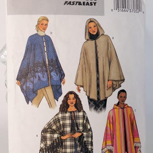 May include: Butterick 3975 sewing pattern envelope featuring illustrations of four different cape styles. Designs include a blue wolf-print cape, a hooded beige cape, a black and white plaid cape with fringe, and a multi-colored striped hooded cape.