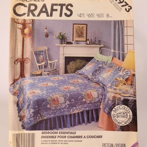 May include: A vintage McCall's Crafts pattern envelope featuring a bedroom ensemble. The pattern shows a bed with a blue floral comforter and matching pillow shams. The envelope includes text such as "Bedroom Essentials" and "Pattern/Patron".