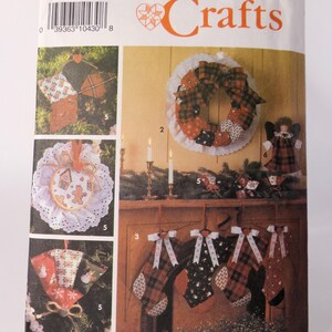 Op de afbeelding: Een Simplicity Crafts naai-patroon voor het maken van kerstversiering. Het patroon bevat instructies voor het maken van een krans, kousen, ornamenten en een pop. Het patroonnummer is 9796.