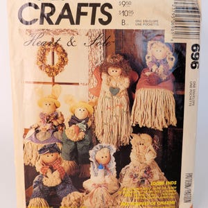 Puede incluir: Un sobre de patrón de costura McCall's Crafts 696 titulado Heart & Sole. El frente presenta ilustraciones de seis muñecas hechas a mano con cabezas de fregona, incluyendo ángeles, conejos y niños, con texto sobre precios e información.