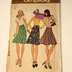 May include: Vintage Simplicity sewing pattern number 6700 for a skirt. The pattern is for size 8, waist 24 inches, and is for misses. The pattern shows three different styles of skirts, all with a wrap-around design. The skirts are shown in green, floral, and brown floral prints.