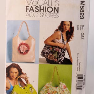 May include: A McCall's Fashion Accessories pattern, M5823, featuring four handbag designs. The bags include a light pink tote with a flower, a black floral tote, a lime green bag with a gold handle, and a floral print bag with a gold chain.