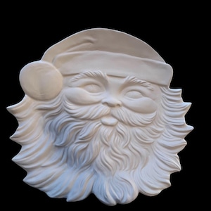 May include: A white, three-dimensional Santa Claus face sculpture. The sculpture features a hat with a pom-pom, a long, flowing beard, and a smiling expression. The background is solid black.