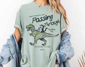 Don&#39;t Mind Me Just Passing Through T Shirt, Funny Cat Riding T-rex Shirt, Cute Gift T Shirt for Cat Lovers and T-Rex Lovers alike