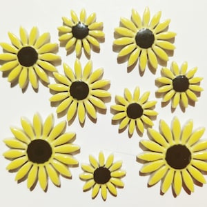 May include: Ten yellow ceramic sunflower tiles with black centers. The tiles are arranged in a random pattern on a white background.